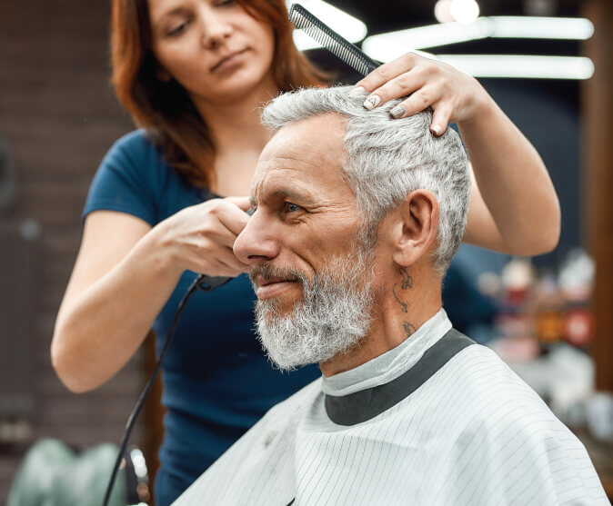 woman cutting senior mans hair
